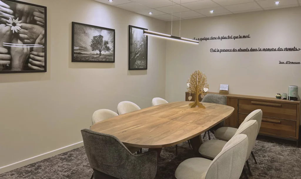 Salle de réunion des familles avec grande table en bois et décoration apaisante.
