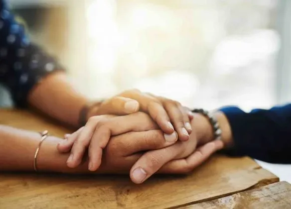 Mains enlacées en signe de soutien et d'accompagnement pendant le deuil.