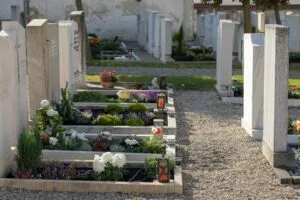 Fleurs fraîches et bougies de recueillement posées sur une pierre tombale.
